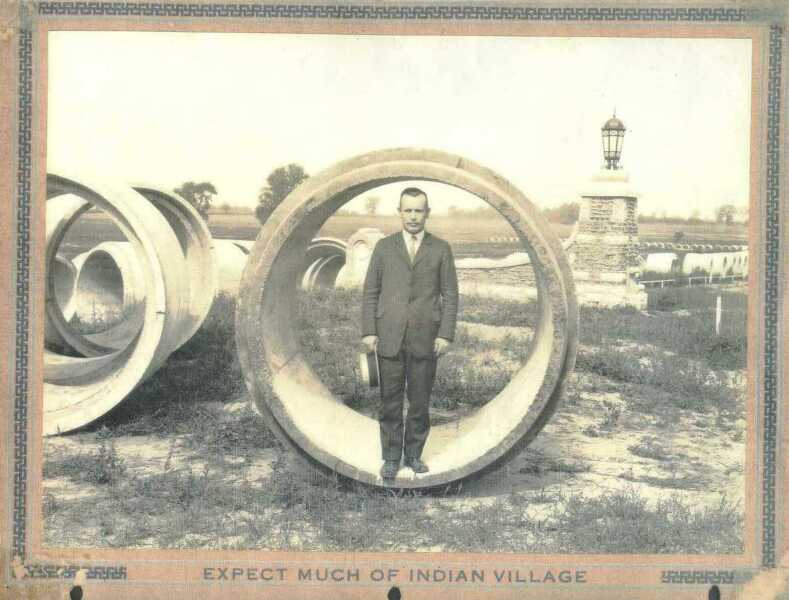 Man standing inside a massive sewer pipe during Indian Village construction, c. 1927